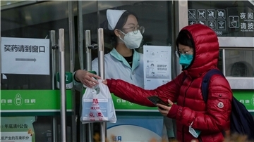 Eine Frau holt in einer Apotheke in Peking COVID-19-Antigen-Kits ab.