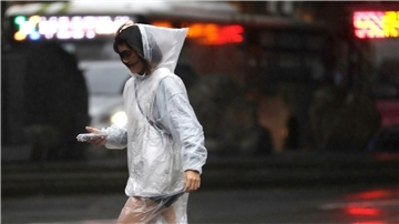 Eine Frau läuft bei Regen und Wind durch Taipeh.