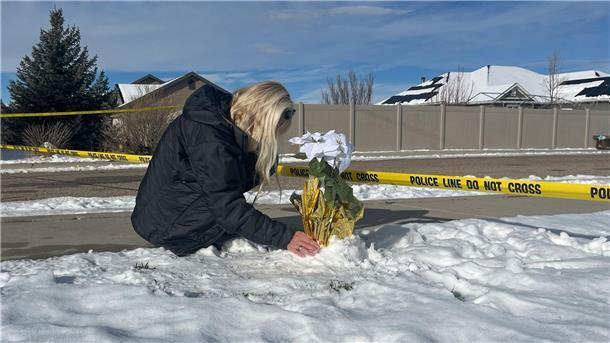Eine Frau legt Blumen vor dem Haus ab, in dem acht Familienmitglieder tot aufgefunden wurden.