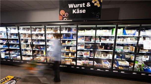 Eine Frau steht vor einem Regal im Supermarkt. Die günstigeren Lebensmittel findet man dort oft weiter oben oder unten.
