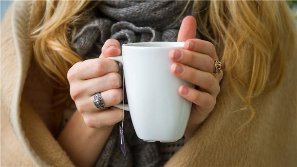 Eine Frau wärmt sich in Hannover, in eine Decke gehüllt, an einer Tasse Tee. Ab wann jemand friert, hängt von vielen Faktoren ab.