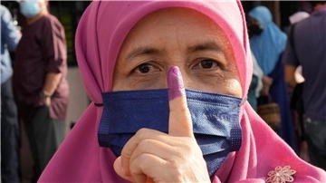 Eine Frau zeigt ihren eingefärbten Finger nach der Stimmabgabe in Seberang Perai.