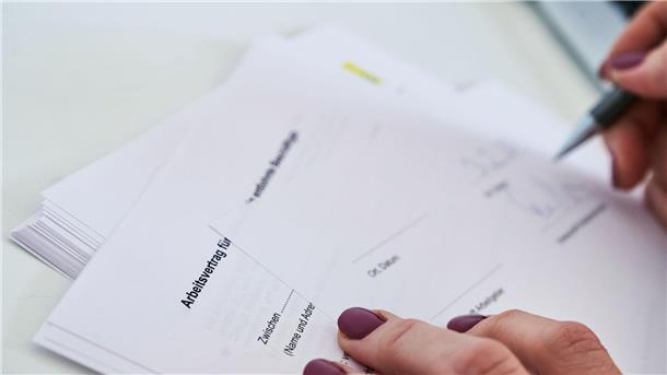 Studie: Frauen auf dem Arbeitsmarkt noch immer benachteiligt Eine Frauenhand unterschreibt einen Arbeitsvertrag.