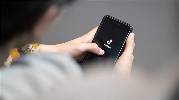 Internet: Hilfswerk sieht „neue Form der Kinderarbeit“ Eine Jugendliche schaut auf ein Smartphone mit angezeigtem TikTok Logo.