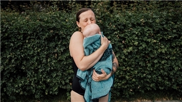 Eine junge Mutter drückt im Freibad ihr Kind an sich. Dieser Moment, den die Fotografin Sophie Kirchner festgehalten hat, drückt innige Verbundenheit aus.