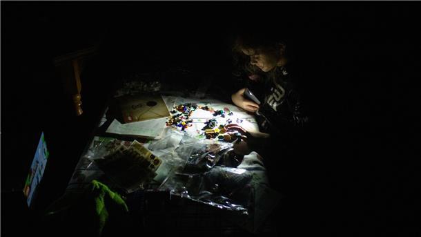 Eine Kindheit im Krieg: Ein Mädchen spielt während eines Stromausfalls mit Lego.