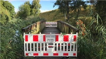 Eine kleine Fußgängerbrücke führt, tritt man durch das einstige Tor der Admiral-Brommy-Kaserne, in eine Grünanlage mit Wegen. Die Brücke ist derzeit gesperrt. Ihr Belag muss ersetzt werden.