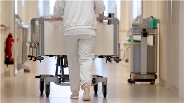 Eine Krankenpflegerin schiebt ein Krankenbett durch einen Flur.