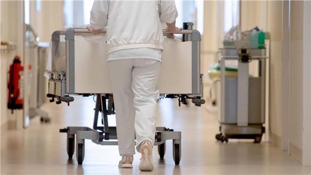 Pflegekräfte in Regelung zu Sterbehilfe einbinden Eine Krankenpflegerin schiebt ein Krankenbett durch einen Flur.