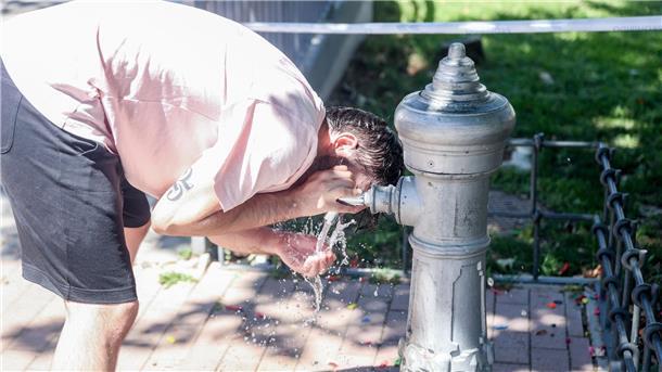 Eine Mann kühlt sich an einem Trinkbrunnen in Madrid ab.