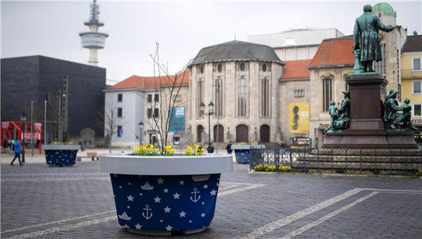 Grün, gelb oder rot? Wir haben die grauen Monsterkübel mal testweise umgefärbt Ein Kübel mit Hafensymbolen darauf ist auf einem öffentlichen Platz zu sehen.