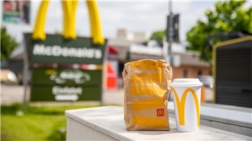 Eine McDonald’s To-go-Tüte und ein dazugehöriger To-go-Becher stehen vor einer Tübinger McDonald’s Filiale.
