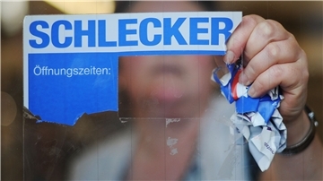 Eine Mitarbeiterin der Drogeriemarktkette Schlecker reißt das Firmenlogo von der Eingangstür einer Filiale.