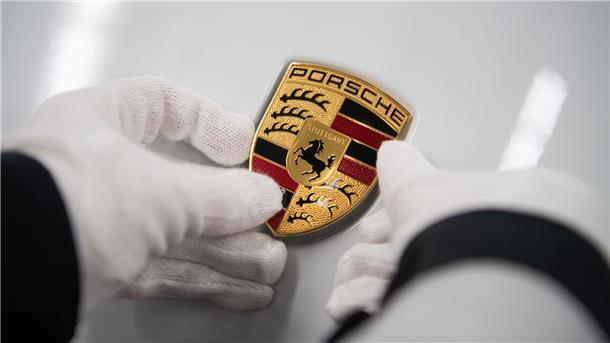 Wenige Monate nach Börsengang: Porsche steigt in den Dax auf Eine Mitarbeiterin der Porsche AG hält in der Produktion ein Porsche-Emblem.