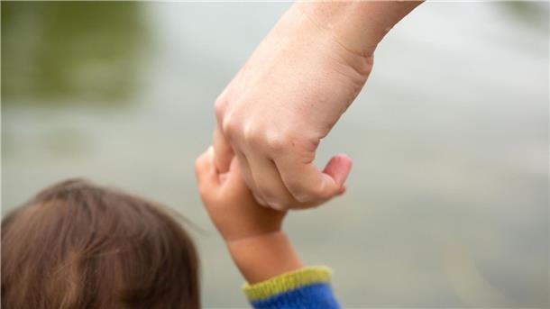 Eine Mutter hält ihr Kind an der Hand.