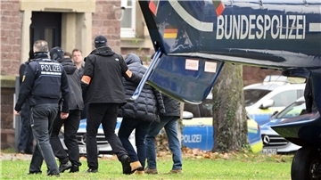 Eine Person (2.v.r.) wird von Polizisten aus einem Hubschrauber gebracht.