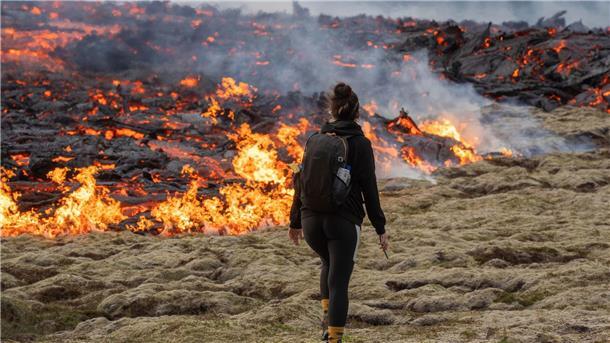 Island erlebt dritten Vulkanausbruch binnen drei Jahren Eine Person geht vor glühender Lava, die aus der Spalte des Vulkans austritt.