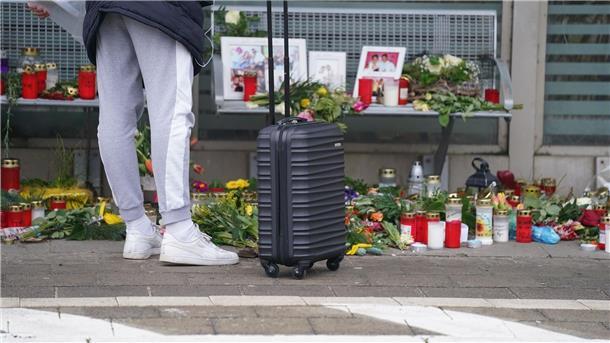 Eine Reisende schaut sich die Blumen, Kerzen und verschiedene Bilder im Wartehäuschen am Bahnhof zum Gedenken an die Opfer der Messerattacke an.