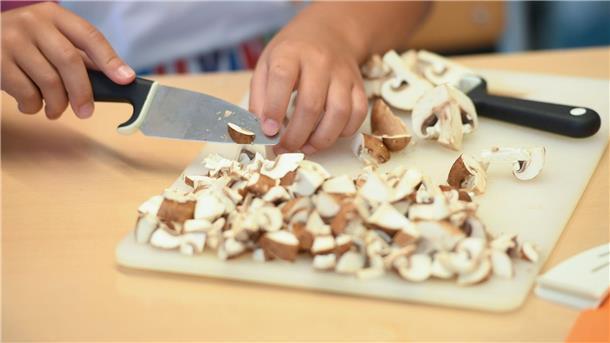 Umfrage: „Ernährung und Gesundheit“ soll auf den Lehrplan Eine Schülerin schneidet während der Koch AG Champignons in kleine Scheiben.