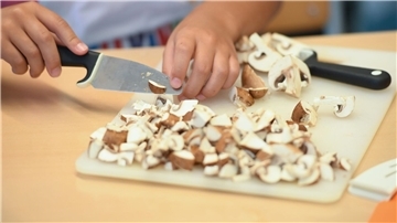 Eine Schülerin schneidet während der Koch AG Champignons in kleine Scheiben.