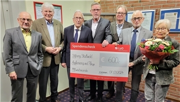 sechs alte Männer und eine alte Frau mit einem Scheck