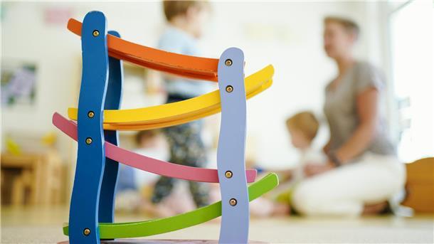 Eine Erzieherin spielt in einer Kindertagesstätte hinter einer Rollbahn mit Kindern.Eine Studie zeigt: Viele Erzieherinnen und Erzieher verlassen den Beruf früh oder reduzieren ihre Stunden. Nur ein Drittel bleibt auch nach zehn Jahren in der Kindertagesbetreuung im Land Bremen tätig.