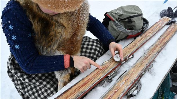 Eine Teilnehmerin wachst ihre Holzskier mit einer Kerze.