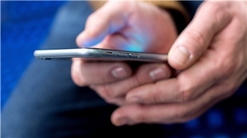 Ein Mann hält ein Handy in den Händen. 