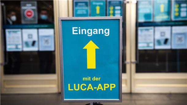„Eingang mit der Luca-App“ steht auf dem Schild vor einem Kaufhaus. Der digitale Service soll bei der Kontaktverfolgung helfen, steht jedoch in der Kritik – es geht um die zentrale Speicherung von Daten.