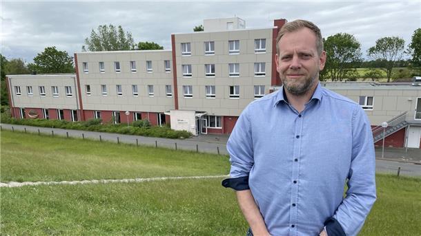 Ein Mann steht vor einem Gebäude.