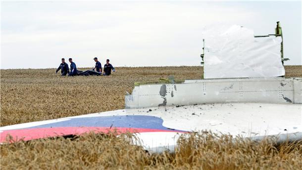 Einsatzkräfte transportieren im Juli 2014 eine Trage mit einem Leichensack durch ein Getreidefeld an der Absturzstelle der Boeing 777 der Malaysia Airlines.