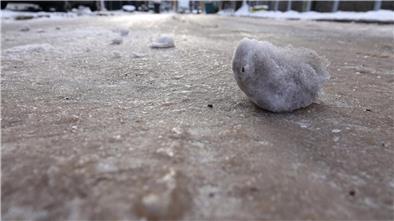 Gefahr für glatte Straßen wegen gefrierender Nässe Eisklumpen liegen auf einer vereisten Straße.