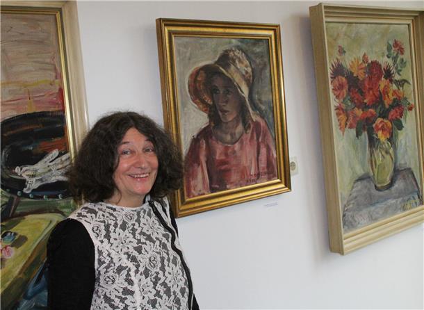 Eine Frau steht vor einer mit Bildern behangenen Wand.