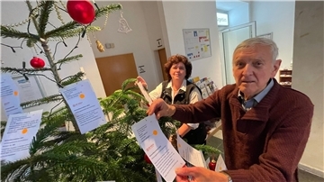 Ellen und Wolfgang Liedtke vom Tafel-Team befestigen die Wünsche am Tannenbaum. Ab Montag können die Kärtchen im Beerster Rathaus abgeholt werden.
