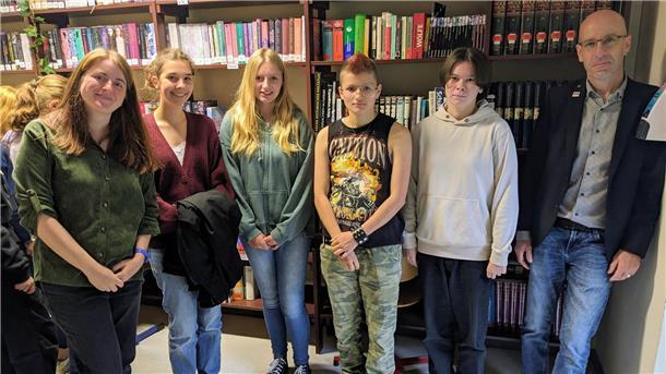 Mehrere Menschen stehen vor einem Bücherregal.