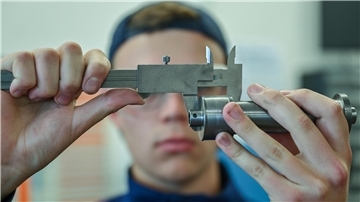 Ein junger Mann hält etwas aus Metall in seinen Händen.