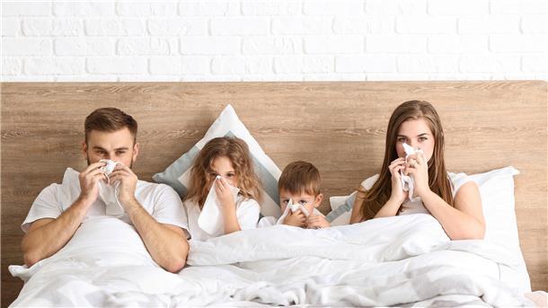 Familie mit Erkältung im Bett