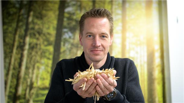 Ein Mann hält Holz in der Hand.