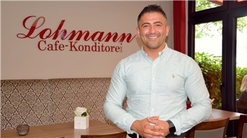 Ein Mann mit Hemd steht in seinem Café.