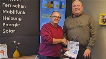 Erster Goldtaler des Jahres: SatCom-Geschäftsführer Harald Stiebitz (rechts) übergibt einen 50-Euro-Einkaufsgutschein als Sofortgewinn an seinen Kunden Ulrich Andres.