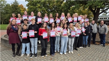 Erwachsene v. l.: Mandy Schaper (Gymnasium Brake), Brigitte Rademacher (IGS Brake), Martina Peters (Polizeistation Elsfleth), Sebastian Jacobs (VBW) und André Gieschen (AllerBus) übergaben den frisch ausgebildeten Busbegleiter:innen ihre Ausweise.