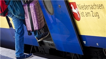 Ein Mann betritt im Hauptbahnhof Hannover mit einem Koffer eine Regionalbahn.