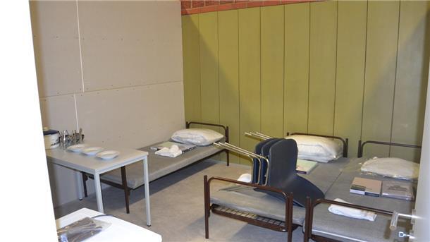 Etwa 15 Quadratmeter misst ein Dreibettzimmer in der Flüchtlingsunterkunft. Es verfügt über Betten, Stühle, Geschirr, Spinde, einen Tisch und einen Kühlschrank. 
