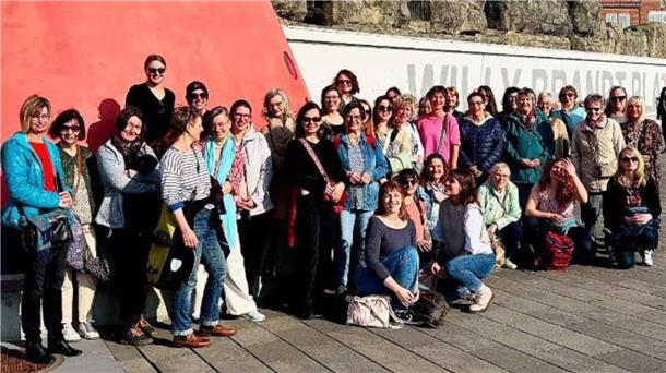 Spaziergang und mehr: Bremerhavens Frauen vernetzen sich Etwa 40 Frauen stehen vor einem Leuchtturm vor dem Zoo am Meer in Bremerhaven.