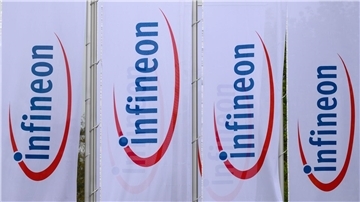Fahnen mit dem Logo von Infineon wehen vor dem Werk des Chipherstllers in Dresden im Wind.