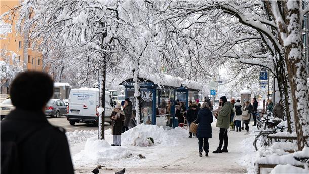 Winterwetter führt zu Flughafen-Stillstand in München Fahrgäste warten an einer verschneiten Haltestelle auf einen Bus.