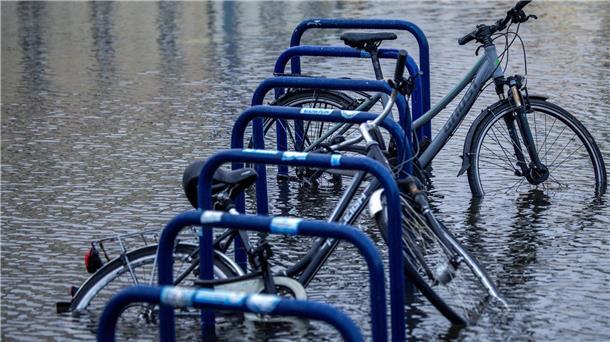 Fahrräder stehen an einer überfluteten Straßenkreuzung in der Nähe des Fischereihafens in Wismar im Wasser.