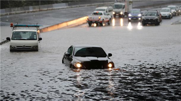 Fahrzeuge stehen im Hochwasser einer überschwemmten Straße im neuseeländischen Auckland.