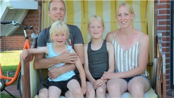 Eine Familie mit zwei Erwachsenen und zwei Kindern sitzen in einem Strandkorb.