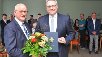Feierlicher Moment: Während Landrat Marco Prietz den Verdienstorden der Bundesrepublik Deutschland und die vom Bundespräsidenten unterschriebene Urkunde an Arnold Renken (links) überreicht, erheben sich die Festgäste von ihren Plätzen.